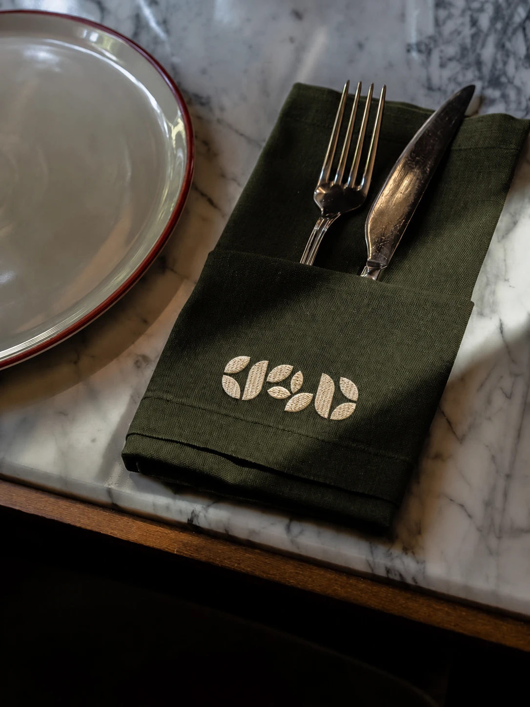 Restaurant place setting with embroidered green napkin, fork, and knife