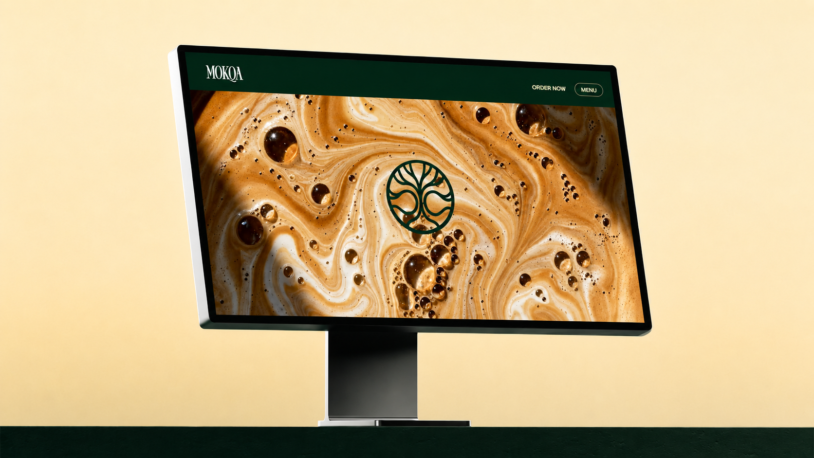 Mokqa homepage displayed on a desktop monitor in a cream and deep green editorial setting