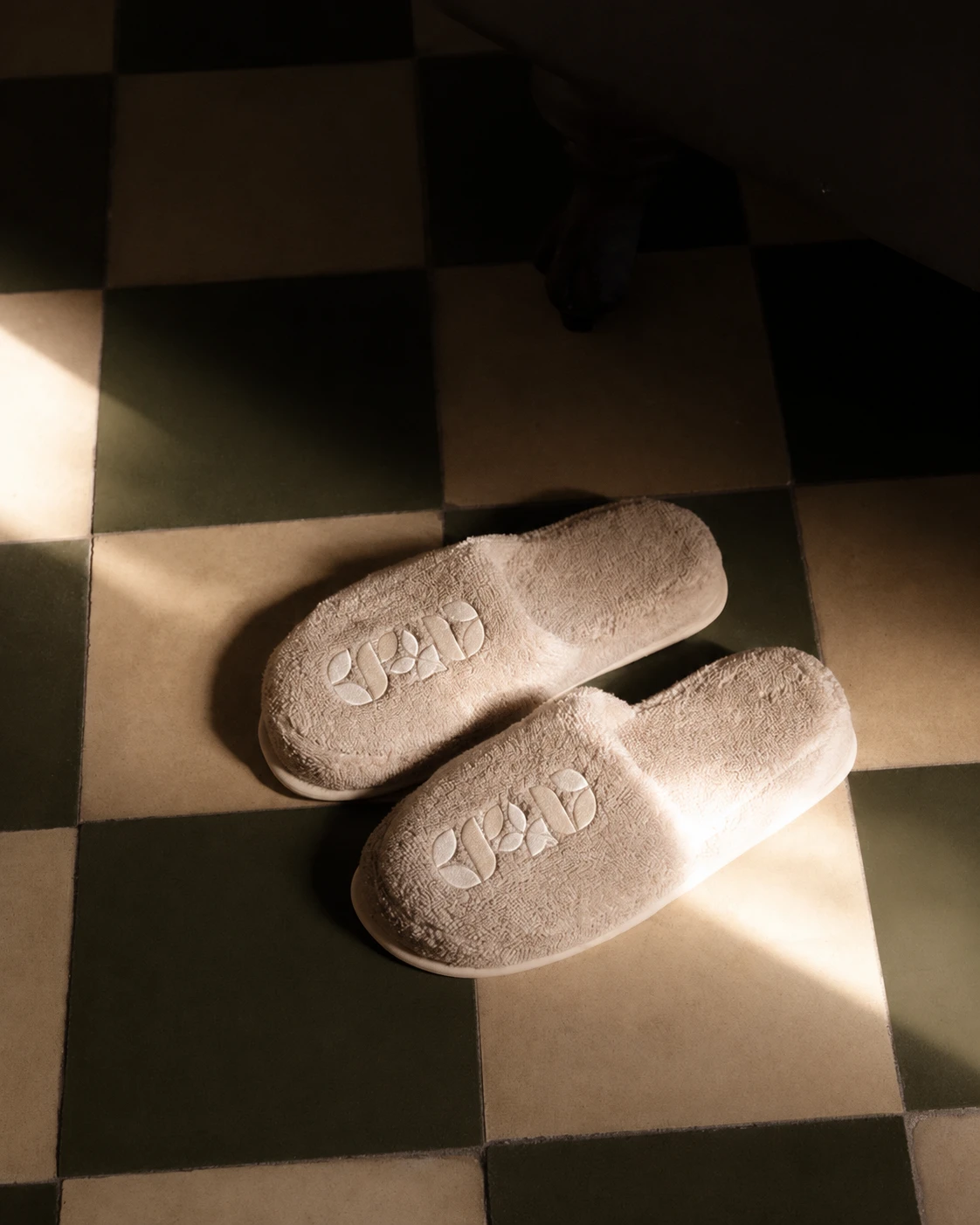 Regal Bee symbol embroidered on resort slippers over a checkerboard floor