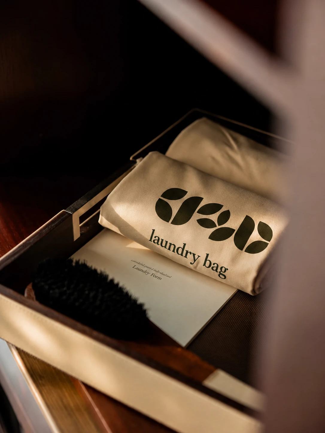 Regal Bee branded laundry bag arranged inside a wooden guest-room drawer